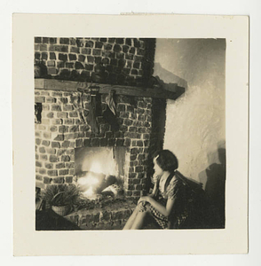 A young girl sitting in front of a fireplace