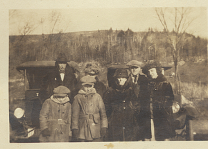Adults and children stand next to cars