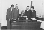 Suffolk University President Gleason L. Archer (1906-1948) with students, alumni and parents at registration, looking at remodeling pictures, photograph, 1940